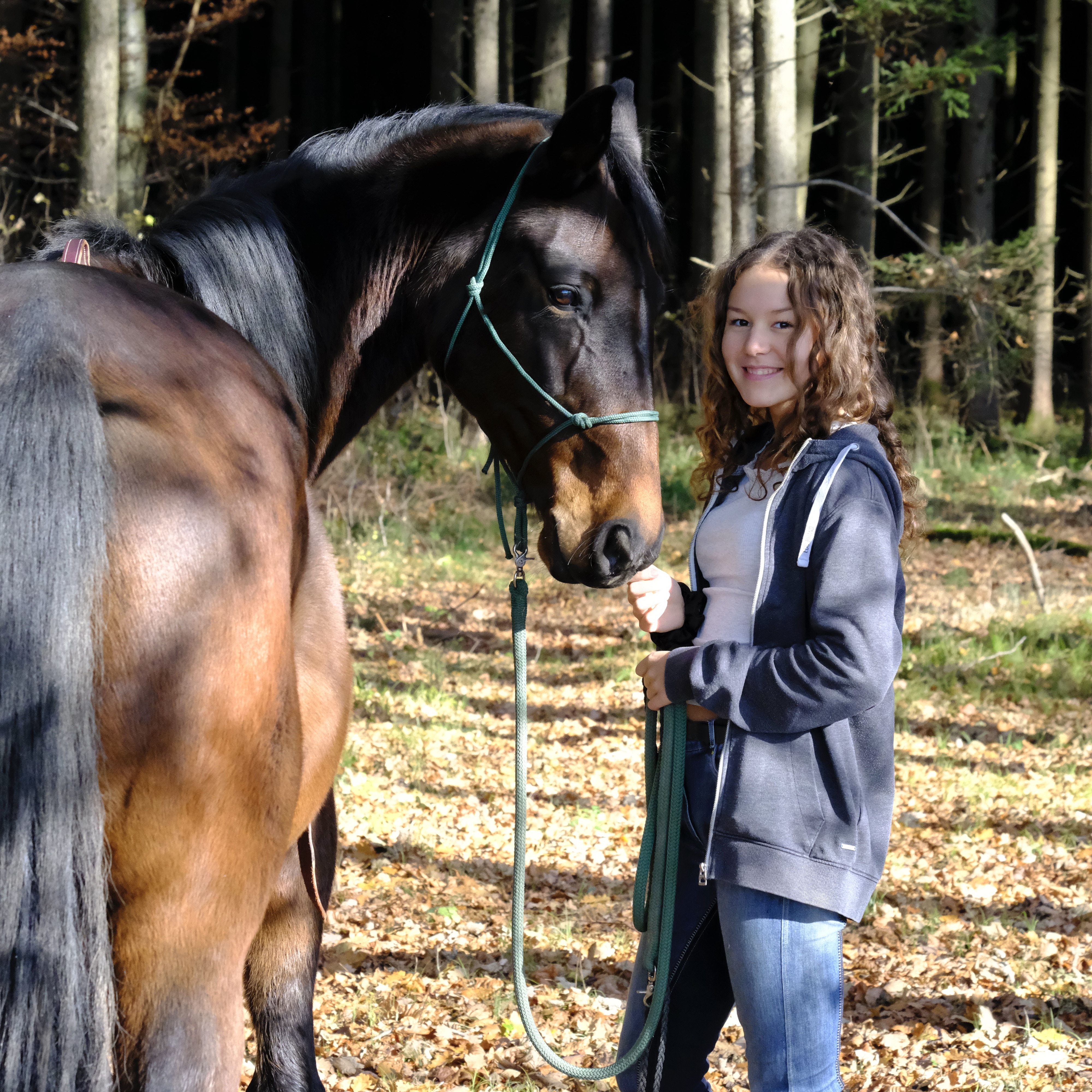 Reitlehrerin und Futterberaterin Dana Künstner lächelt in die Kamera während ihr Pferd sich ihr vertrauensvoll zuwendet