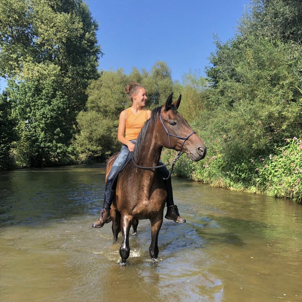 Dana Künstner reitet ihr Pferd ohne Sattel beim Baden im Bach – Vertrauen und Gelassenheitstraining